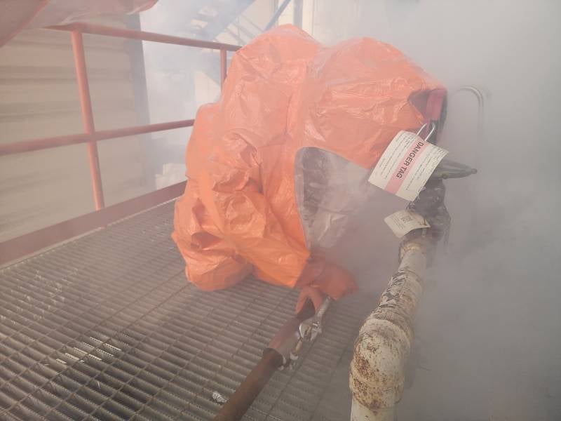 An orange chemical spill suit, partially obscured by steam